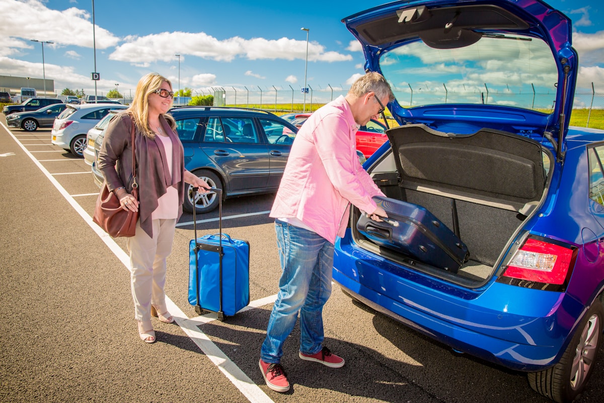 Family loading luggage into a vehicle at an airport departure area